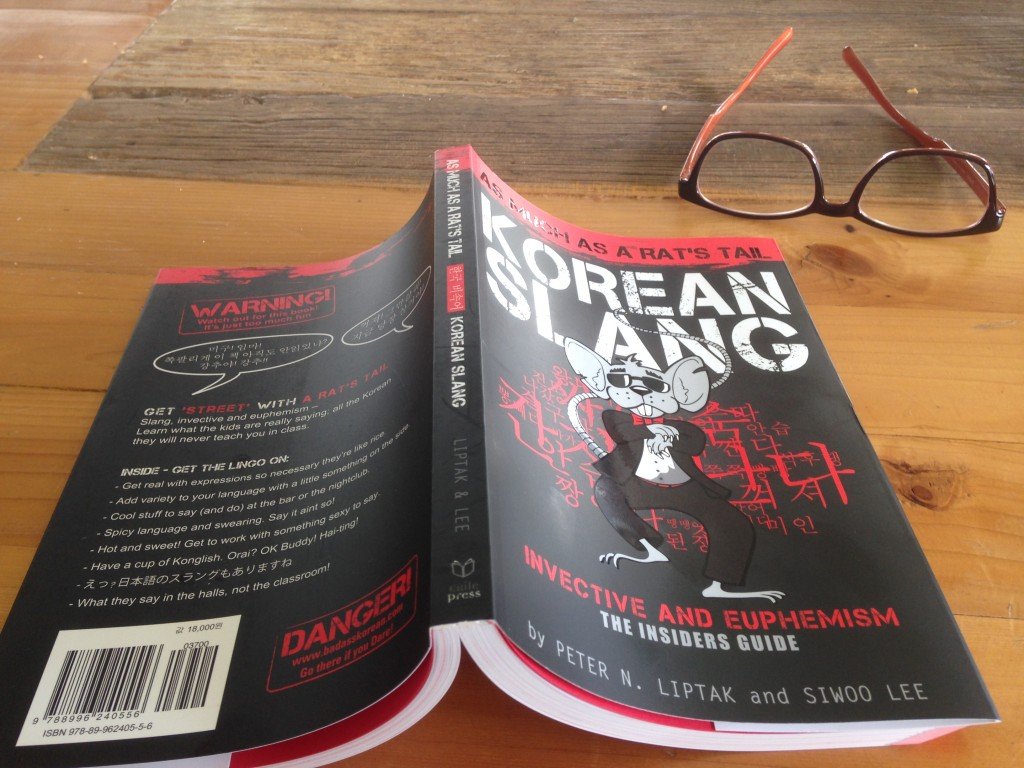 Korean Slang book open on table with glasses